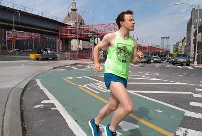A runner in a bike lane with the Wiliamsburg Bridge in the background